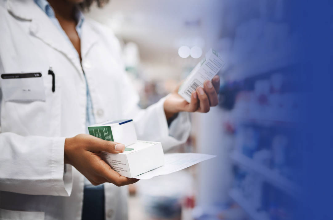 Pharmacist holding a paper and two medicine boxes in one hand and one medicine box in other