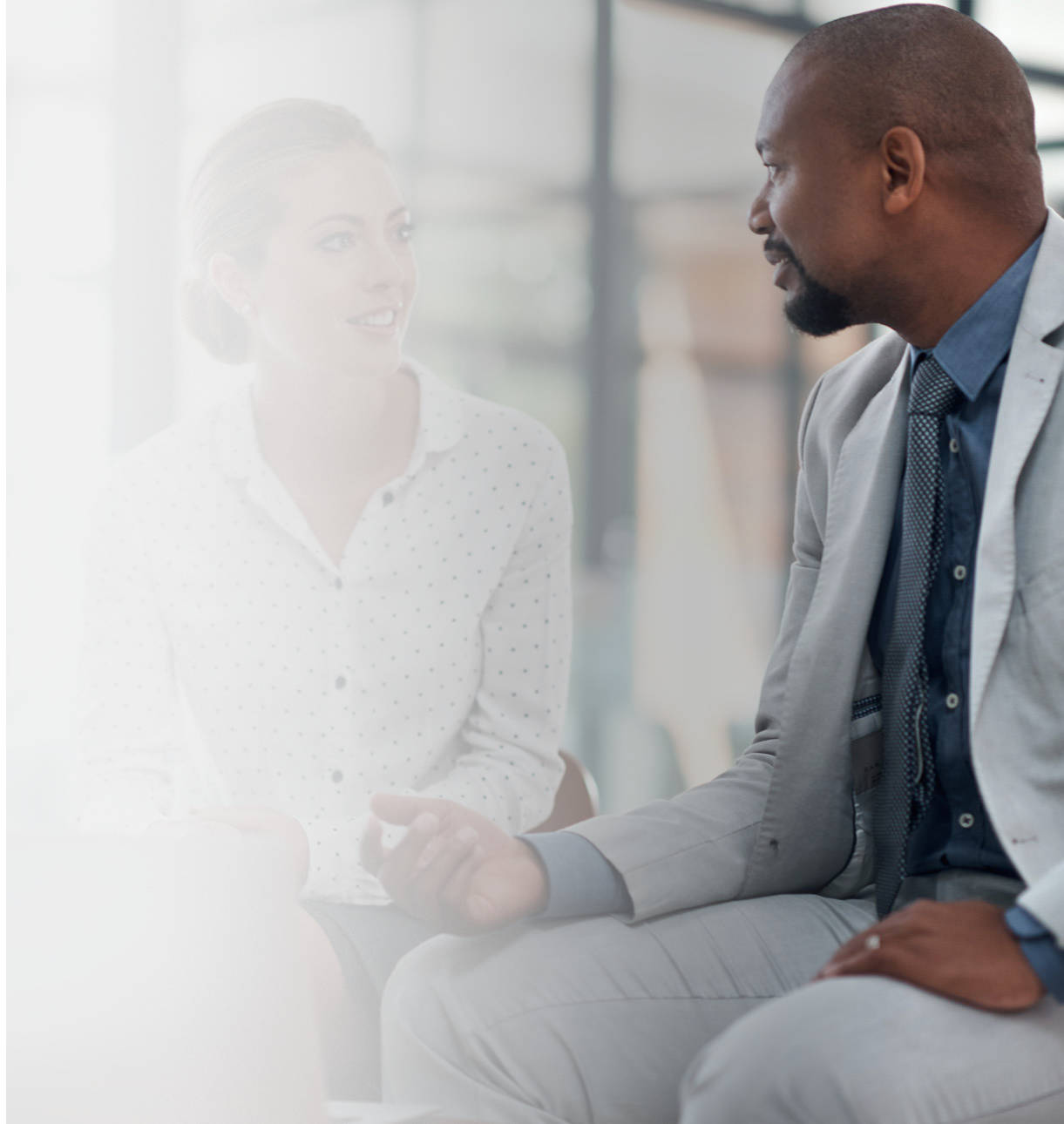 A man and woman coworker sitting down and engaging in conversation