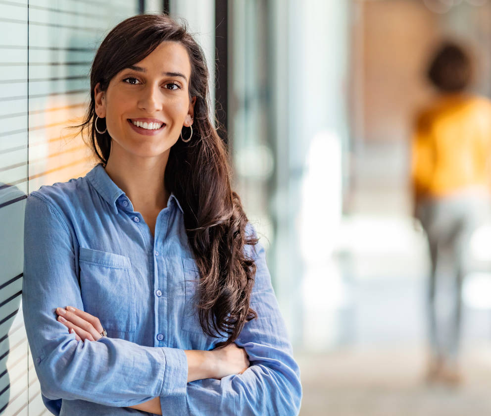 Woman professional wearing blue shirt and smiling at camera with arms crossed