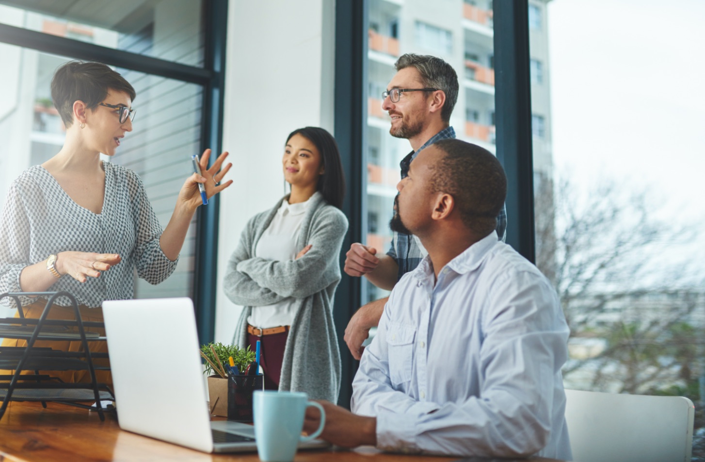 Woman colleague presenting to another woman and three men by a table