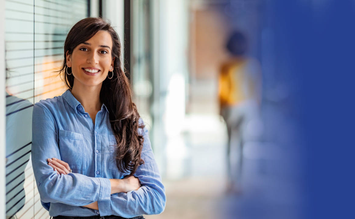 Woman professional wearing blue shirt and smiling at camera with arms crossed