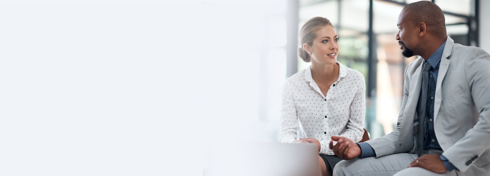 A man and woman coworker sitting down and engaging in conversation