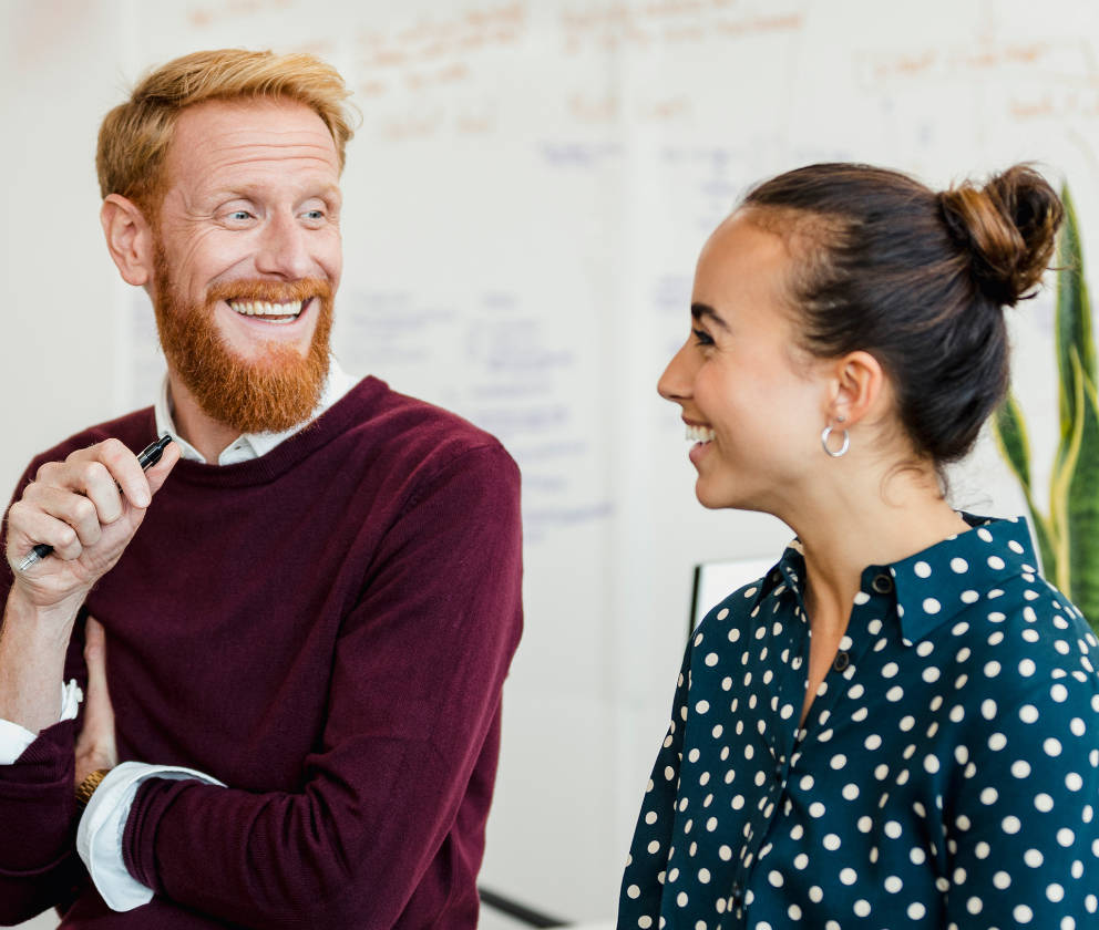 A man and woman coworker smiling and laughing with one another