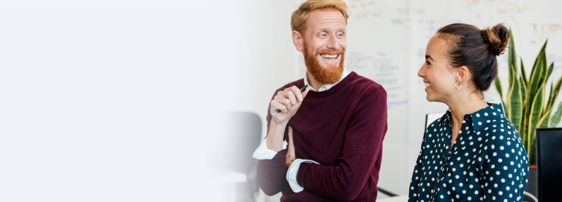 A man and woman coworker smiling and laughing with one another